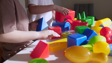 kids girl and baby play in kindergarten. a group of children play toys cubes and cars on the table in indoor kindergarten. happy family preschool education concept. nursery boy baby toddler home