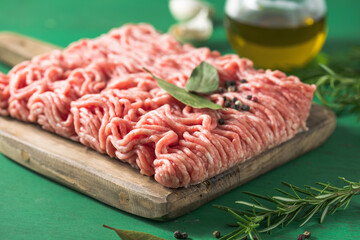 Raw Mince, minced Ground beef meat on a cutting board. Green background. Top view