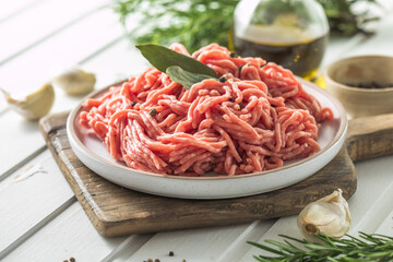 Fresh Raw Beef Minced Meat with herbs and rosemary on wooden board on a light background, banner,...