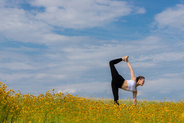 Fototapeta na wymiar 夏の黄色い花が咲いている公園でヨガを練習している女性の姿