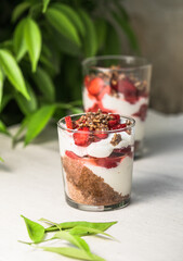 Breakfast layered parfait dessert with yogurt, sponge biscuit and fresh strawberry, white background copy space