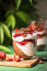 Breakfast layered parfait dessert with yogurt, sponge biscuit and fresh strawberry, white background copy space