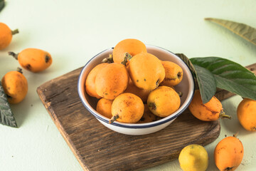Ripe medlar fruit , Eriobotrya japonica, and green medlar leaves on wooden table. Top view