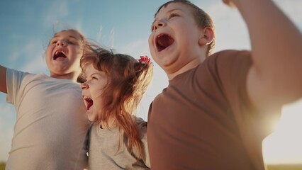 group of kids team hugging a jumping and rejoicing outdoors. happy family teamwork kid dream concept. family children sisters brothers have sun fun hugging in the park in nature