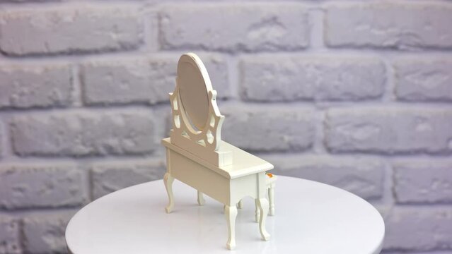 White wooden nightstand with mirror and tiny tabouret. Furniture at the rotating table at white backdrop. Close up.