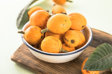 Ripe medlar fruit , Eriobotrya japonica, and green medlar leaves on wooden table. Top view