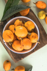 Ripe medlar fruit , Eriobotrya japonica, and green medlar leaves on wooden table. Top view
