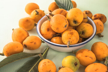 Ripe medlar fruit , Eriobotrya japonica, and green medlar leaves on wooden table. Top view