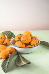 Ripe medlar fruit , Eriobotrya japonica, and green medlar leaves on wooden table. Top view