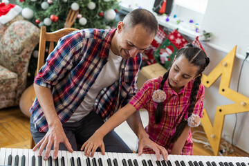 Obraz premium father and daughter at the piano with Christmas decor