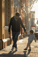 dad and son are walking in the city at sunset, they are walking around the city and dancing. dad spends time with his son, The concept of a happy family