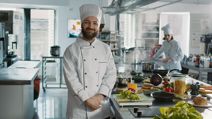 Portrait of male chef looking at camera in professional kitchen, preparing to make culinary recipe with gourmet food. Authentic cook working in restaurant cuisine, gastronomy dish.