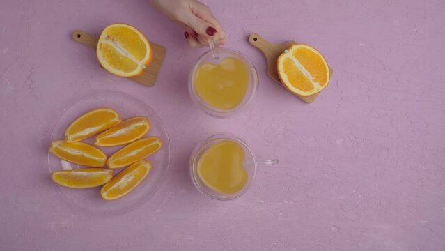 Glass of orange juice with oranges top view, amaranth pink background. Flat lay. Love for fruits, healthy food. Vertical video
