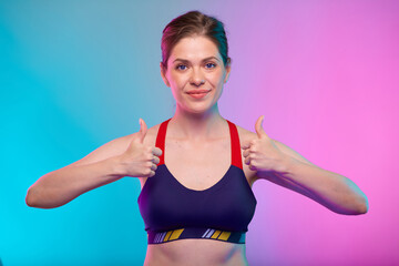 Sporty woman in sports bra wear with thumbs up. Female fitness portrait isolated on neon color background. Healthy lifestyle concept with yoga instructor.