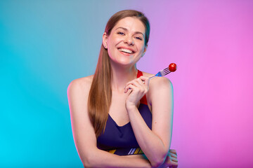 Happy smiling sporty woman in fitness sportswear with red tomato on fork. Female fitness portrait isolated on neon multicolor background.