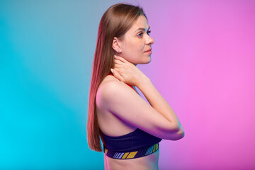 Profile portrait of sporty woman in fitness bra touching her neck. Female fitness portrait isolated on neon multicolor background.
