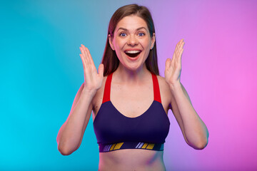 Amazed sporty woman in fitness sportswear holding hands up. Female fitness portrait isolated on neon multicolor background.