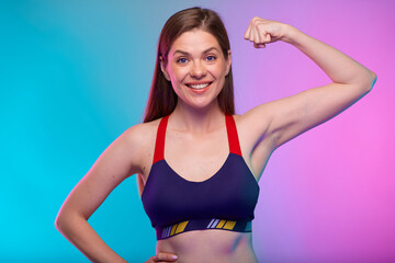 Fototapeta na wymiar Smiling sporty woman in fitness sportswear flexes arm and demonstrates muscles. Female fitness portrait isolated on neon multicolor background.