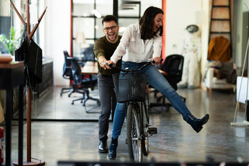 Fototapeta na wymiar Colleagues in office. Businesswoman and businessman with bicycle. Two friends having fun together