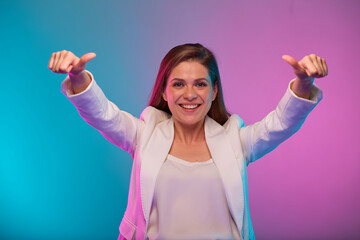 Fototapeta premium Smiling business woman with two hands up and thumbs, portrait with neon lights colors effect. Female model isolated on neon colored background wearing white suit.