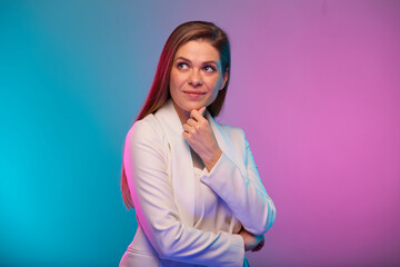 Thinking business woman touching her face, portrait with neon lights colors effect. Female model on neon colored background wearing white suit.