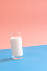 A glass of milk on blue and pink background.