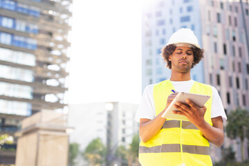 Young arhitect with helmet. Man using digital tablet