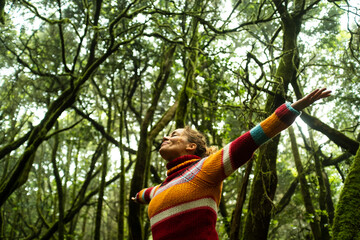 Ground view of joyful woman with arms up standing in the deep forest. Nature environment activist...