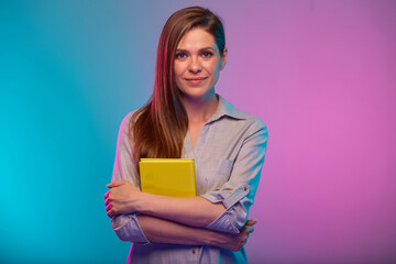 Confident teacher or student woman holding yellow book, portrait with neon lights colors effect....
