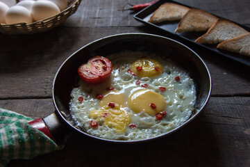 Breakfast item fried eggs in a frying pan on a background. Close up, selective focus.