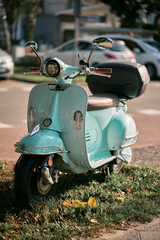 Close up of a vintage light blue retro moped parked on the street.