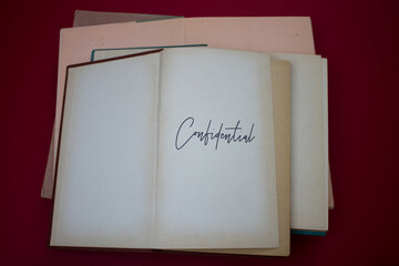 Confidential word in opened book with vintage, natural patterns old antique paper design.