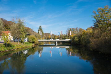 Fototapeta na wymiar concrete bridge over Loisach river, with flagposts, reflecting in the water. bavarian landscape