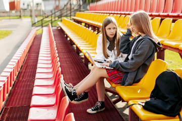 Happy schoolgirls do homework together in the school stands after school. The concept of training and education, modern technologies