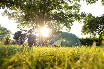 Bicycle with panniers next to a tent at sunset 