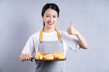 Young Asian woman holding bread on background