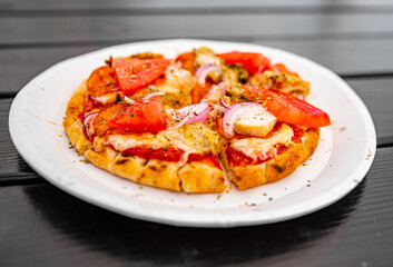 mini pita pizza with Mozzarella cheese, ham, mushrooms, salami. Italian pizza on wooden table background outdoor