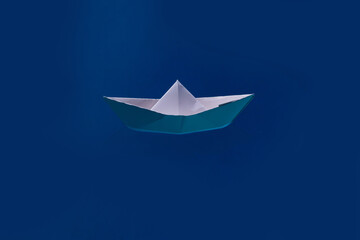 Paper boat sailing on blue water surface. Paper ship. Paper boat in blue sea background. Tourism,...