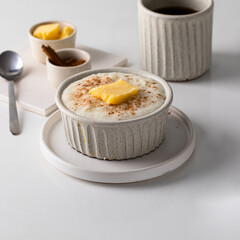 Traditional Scandinavian breakfast, Risengrod or  rice pudding or porridge with butter and cinnamon on kitchen table .
