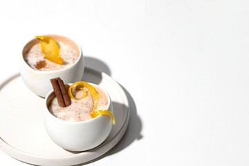Traditional Spanish dessert arroz con leche or rice pudding decorated with lemon and Cinnamon on white background with shadow.Copy space