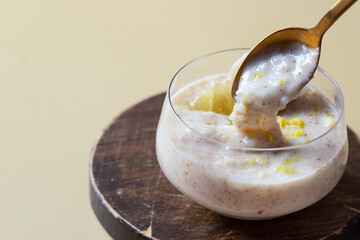 Close up of Spanish dessert arroz con leche or creamy rice pudding decorated with lemon slice and cinnamon stick on beige background.