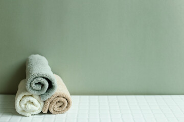 Obraz na płótnie Canvas Bathroom towel on white table. khaki green wall background. skin care and spa concept