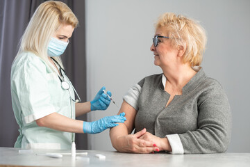 Fototapeta premium Closeup nurse doing vaccine injection to senior woman.