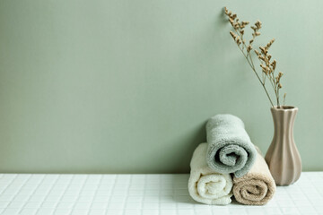Bathroom towel and dry flower on white table. khaki green wall background. skin care and spa concept