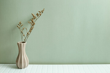 Vase of dry flowers on white table. khaki green wall background - obrazy, fototapety, plakaty