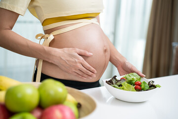 Close up of Asian woman pregnant standing and holding mix slad bowl.