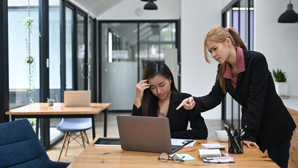 Furious female manager scolding young frustrated young employee with bad work results. Emotional pressure, stress at work
