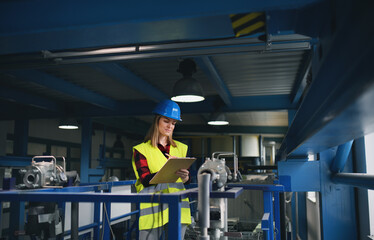 Portrait of female engineer working in industrial factory, doing checkup control.