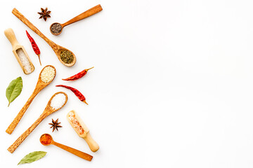 Cooking background with colorful spices and herbs in wooden spoons, top view