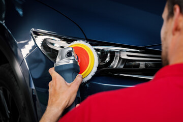 man polishing car headlight with polish machine. restore vehicle lights